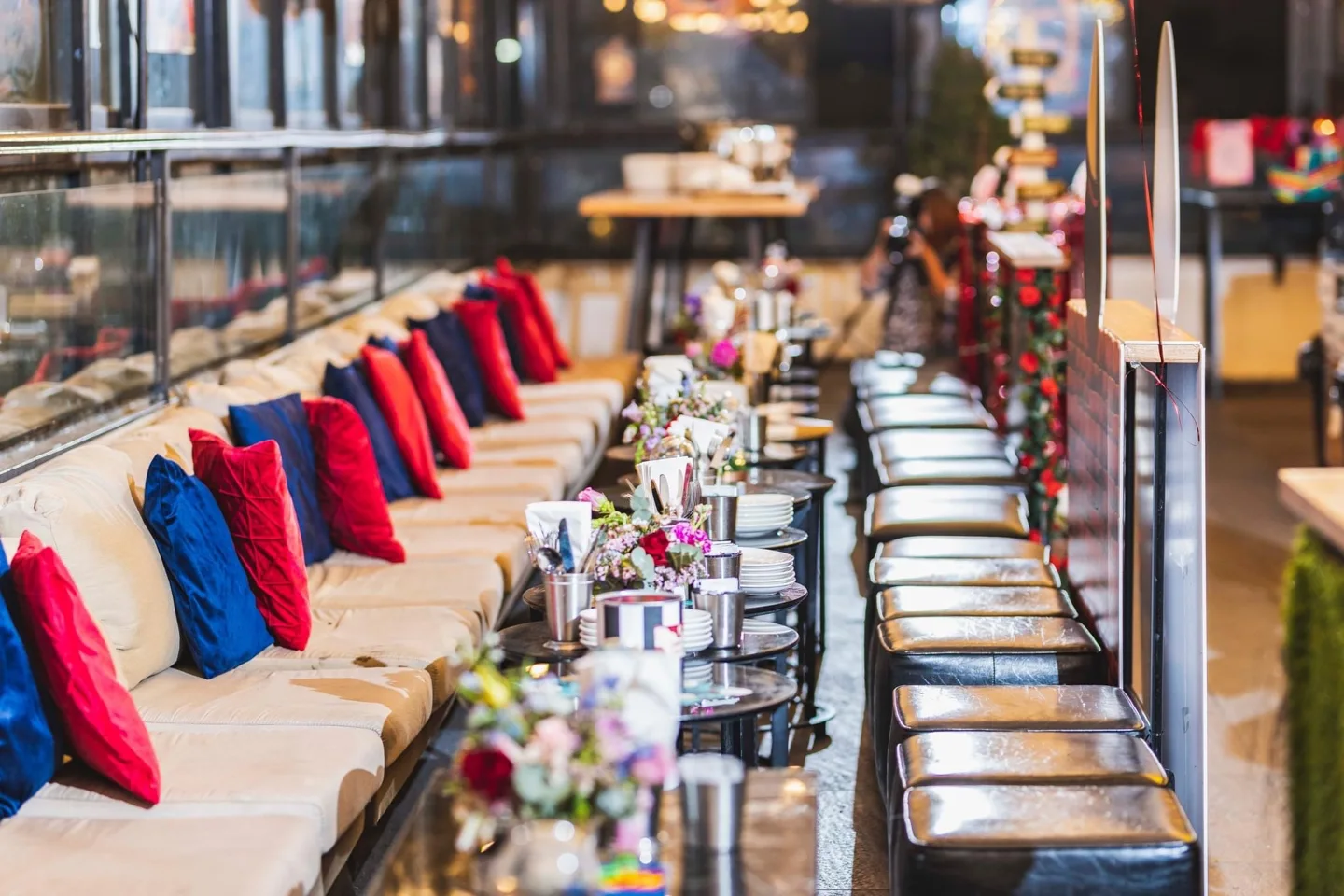 Lounge seating with red cushions, flowers and small tables